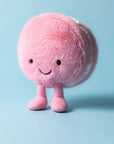 Peluche Amuseables Mia Macaron Framboise Jellycat, debout sur fond bleu