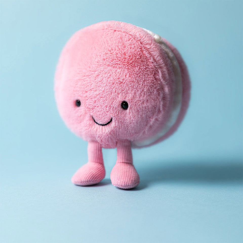 Peluche Amuseables Mia Macaron Framboise Jellycat, debout sur fond bleu