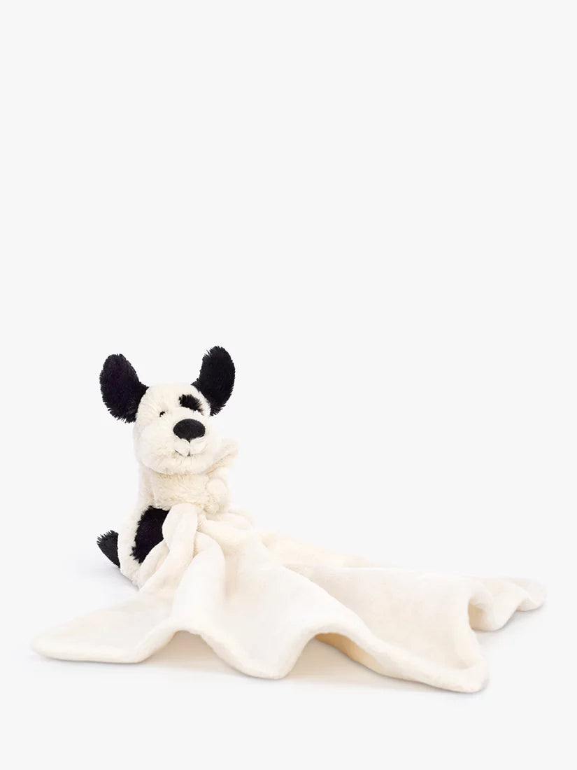 Doudou Bashful Black & Cream Puppy Soother Jellycat, doudou posé sur sa couverture